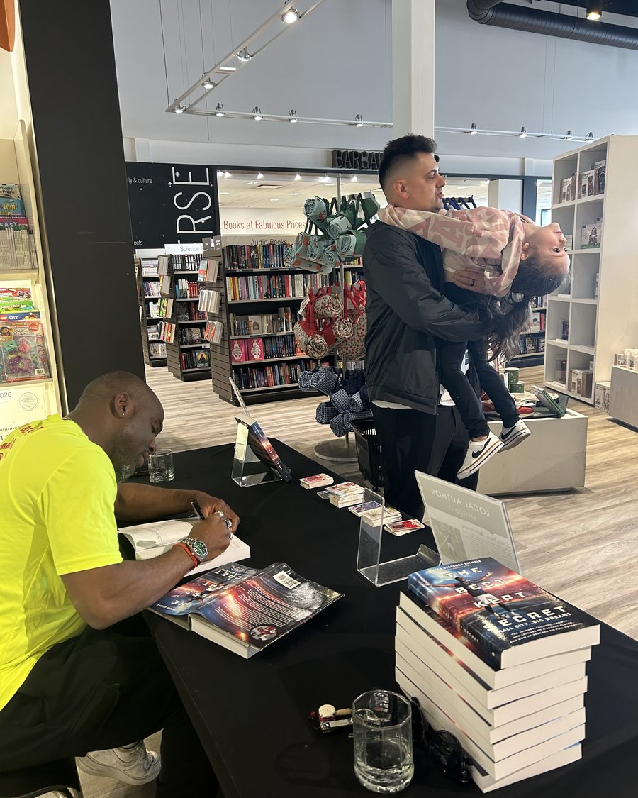 Stephen Ademolu signing copies of The Best Kept Secret at a local-author book launch